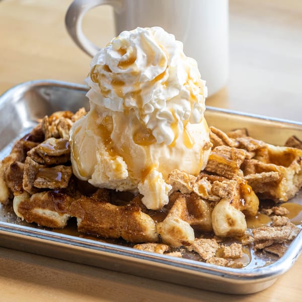 Cinnamon waffle topped with vanilla ice cream, whipped cream, caramel drizzle, and cereal crumbles.