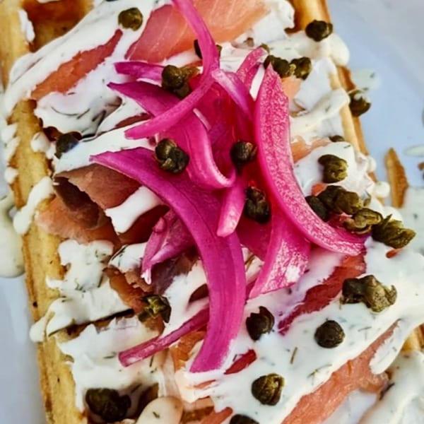 A Munch Munch Waffles & More waffle topped with smoked salmon, pickled red onions, capers, and dill sauce.
